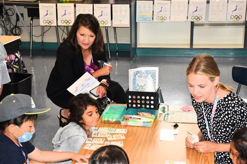 Chief Academic Officer Dr. Heather Donaldson observing students at table with their teacher